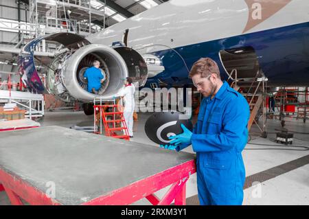 Uomo che tiene parte dell'aereo nell'hangar Foto Stock