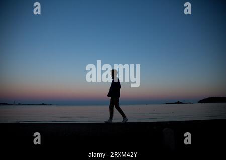 Silhouette di uomo a camminare sulla spiaggia al tramonto Foto Stock
