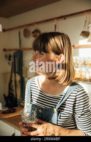 Giovane donna sorridente che regge un bicchiere d'acqua Foto Stock