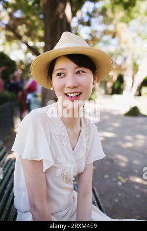 Giovane donna sorridente che indossa un cappello di paglia Foto Stock