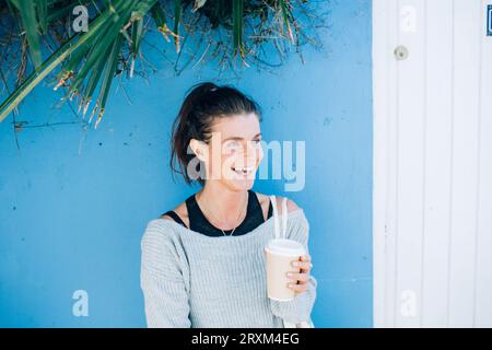 Sorridente donna adulta che tiene una tazza di caffè da asporto Foto Stock
