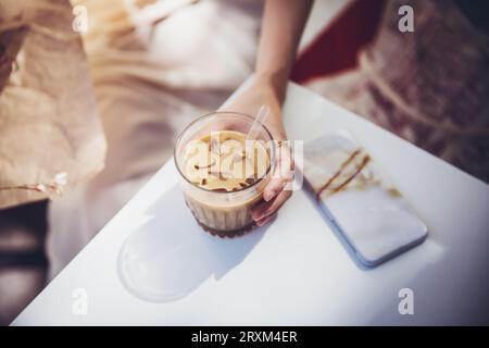 La mano di una donna che tiene un caffè freddo Foto Stock