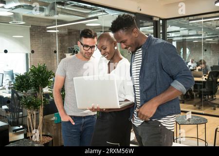 I colleghi utilizzando il computer portatile in ufficio Foto Stock