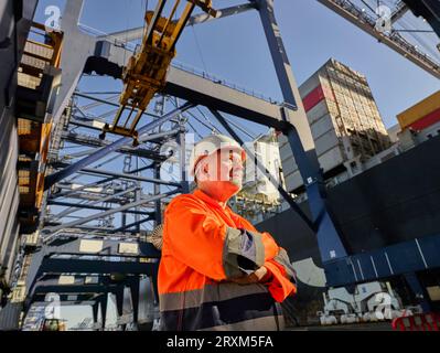 Basso angolo vista di lavoratori portuali al di sotto di una gru a porto di Felixstowe, Inghilterra Foto Stock