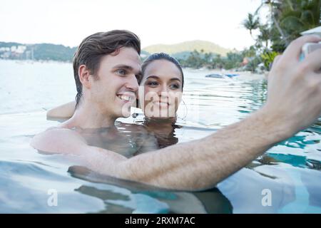 Coppia giovane tenendo selfie in piscina Foto Stock