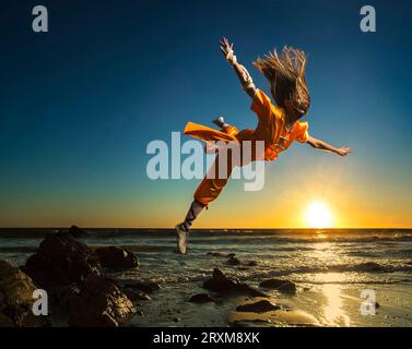 Giovane donna che si tuffa in arti marziali uniforme sulla spiaggia Foto Stock