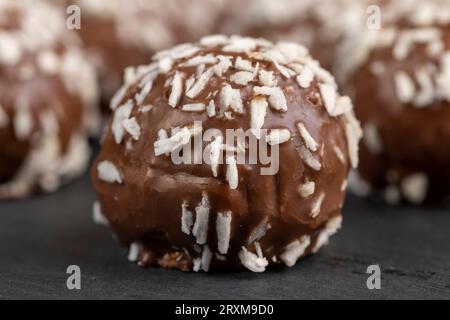 Caramelle al cioccolato in forma di palline con latte di cocco farcitura cosparsa di fiche di cocco, deliziose e morbide torte al cioccolato di cocco di piccolo siz Foto Stock