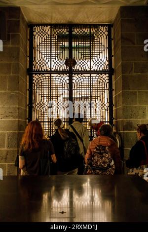 I visitatori guardano attraverso un reticolo nella cripta della cattedrale presso la tomba degli Arcivescovi di Colonia, Colonia, Germania. Besucher Schauen in der Kry Foto Stock