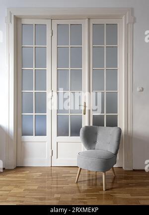 Design moderno degli interni con parete mock-up vuota e mobili grigi, loft e soggiorno in stile vintage. Poltrona, porta, parquet sul pavimento, ag Foto Stock