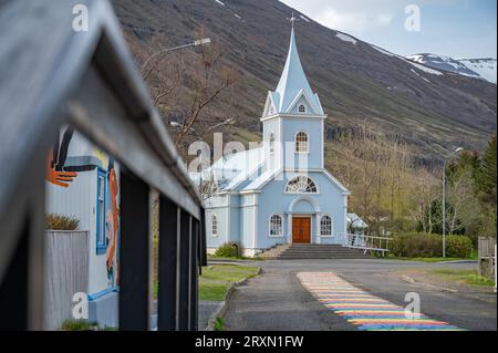 Chiesa con Rainbow Road a Seydisfjordur, Islanda, recinzione di legno di fronte Foto Stock