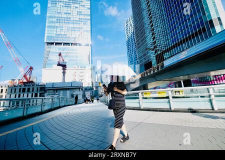 Una donna con un ombrello cammina lungo una passerella sopraelevata a Shibuya, Tokyo, Giappone Foto Stock