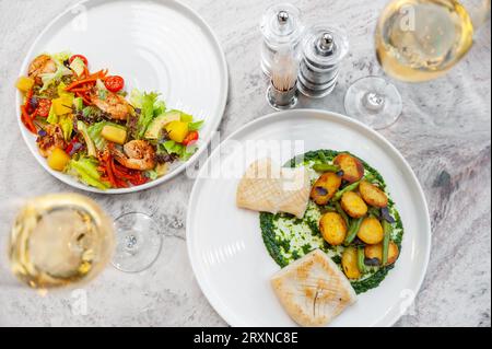 Calamari fritti con salsa di spinaci, patate al forno e asparagi su un piatto bianco. Foto di alta qualità Foto Stock