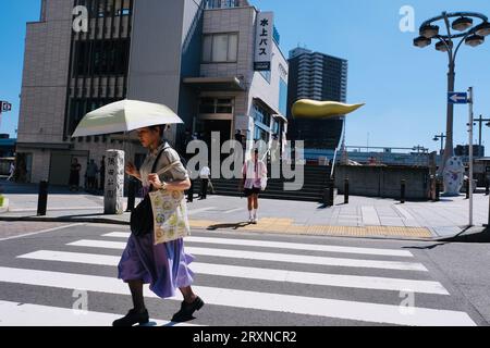 Una donna illuminata dal sole che regge un ombrello cammina attraverso un ponte ad Asakusa, a Tokyo, in Giappone Foto Stock