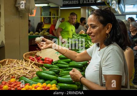 Una donna acquista l'aglio in una bancarella di verdure al mercato al coperto Montrouge Sunday Market, nei sobborghi di Parigi, in Francia. Foto Stock