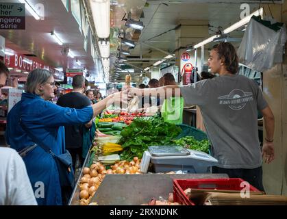 Una donna compra verdure al mercato interno Montrouge Sunday Market, nei sobborghi di Parigi, in Francia. Foto Stock