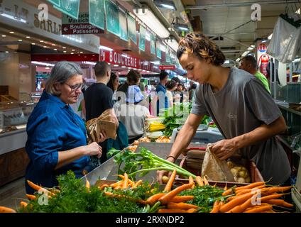 Una donna acquista patate e altre verdure al mercato interno di Montrouge, nei sobborghi di Parigi, in Francia. Foto Stock