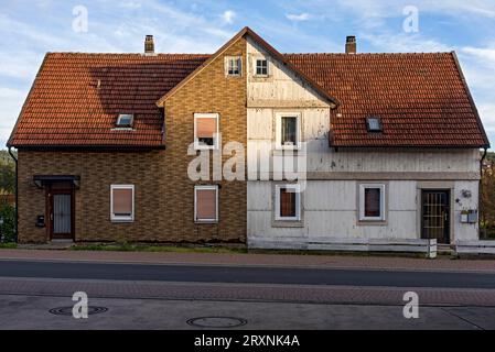 Vecchia casa bifamiliare, degradata, facciata fatiscente, abitazione divisa in due metà, rivestimento in clinker imitazione in plastica e legno Foto Stock