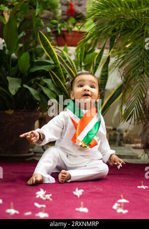 simpatico bimbo con bandiera tricolore indiana in un panno tradizionale con un'espressione facciale innocente Foto Stock