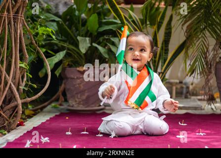 simpatico bimbo con bandiera tricolore indiana in un panno tradizionale con un'espressione facciale innocente Foto Stock