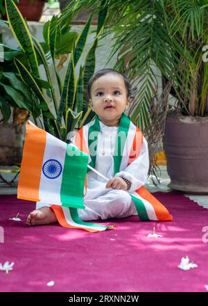 simpatico bimbo con bandiera tricolore indiana in un panno tradizionale con un'espressione facciale innocente Foto Stock