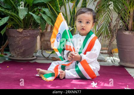 simpatico bimbo con bandiera tricolore indiana in un panno tradizionale con un'espressione facciale innocente Foto Stock