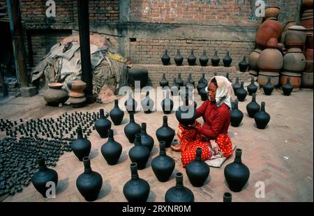 Donna che decora brocche di terracotta al mercato della ceramica, Potters' Square, Potters' Market, Bhaktapur, Nepal Foto Stock