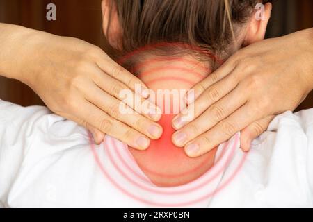 Una ragazza tiene le mani dietro il collo a casa, mal di collo, dolore acuto al collo Foto Stock