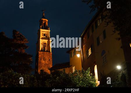 Torre dell'orologio illuminata ed edifici colorati al crepuscolo nel villaggio di Portmeirion, Galles Foto Stock
