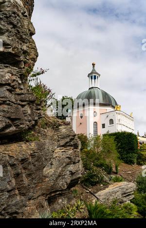 Edificio a cupola rosa con cupola di rame verde incorniciata da antiche mura in pietra nel villaggio di Portmeirion Foto Stock