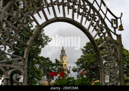 Arcata di ferro ornata che incornicia lo storico campanile del villaggio di Portmeirion, Galles Foto Stock