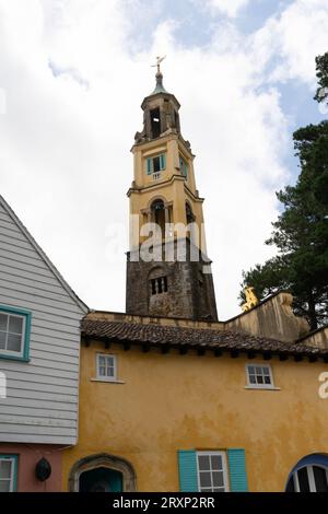 Storico campanile che sorge sopra colorati edifici in stile mediterraneo nel villaggio di Portmeirion Foto Stock