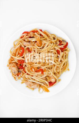 Tagliatelle coreane Udon con carne su un piatto bianco. Deliziosa colazione a base di carne piccante. Foto Stock