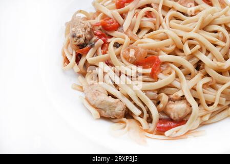 Tagliatelle coreane Udon con carne su un piatto bianco. Deliziosa colazione a base di carne piccante. Foto Stock