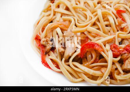 Tagliatelle coreane Udon con carne su un piatto bianco. Deliziosa colazione a base di carne piccante. Foto Stock