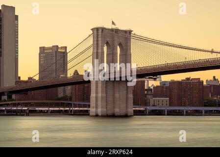 Incredibile vista dell'ora d'oro sul ponte gigante di Brooklyn sul fiume East nella città di New York. Questo ponte collega Manhattan a Brooklyn. Foto Stock