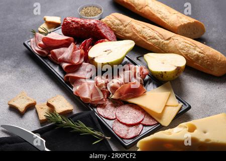 Tavola con assortimento di gustosi salumi, formaggi e pane su sfondo grunge Foto Stock