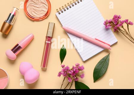 Composizione con cosmetici per il trucco, splendidi fiori e quaderno su sfondo beige Foto Stock