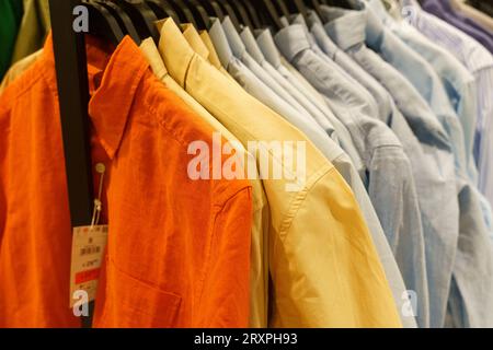 Le luminose maglie da uomo con maniche lunghe sono appese ad appendiabiti in un negozio di abbigliamento. Primo piano. Foto Stock