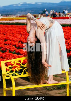 Bruna a pelo lungo che si piega all'indietro sulla panca davanti al campo di tulipano Foto Stock