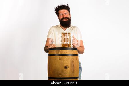 Oktoberfest festival. Uomo sorridente che assaggia birra alla spina. Birra artigianale al ristorante. Uomo barbuto con tazza di birra su botte di legno. Birreria e bar. Germania Foto Stock