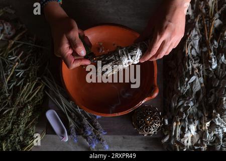 Accendendo un incenso, strega alla vigilia di tutti i santi che esegue un rituale di pulizia, Halloween, credenze spirituali, magia bianca Foto Stock