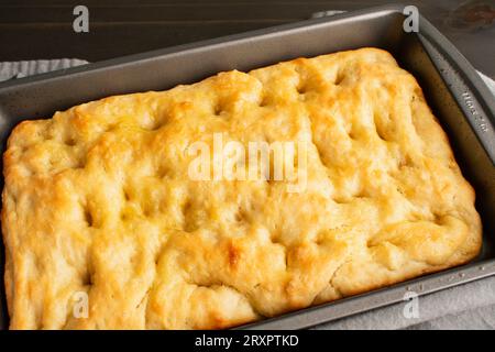 Focaccia appena sfornata in una padella poco profonda: Pane italiano appena sfornato in una padella metallica Foto Stock