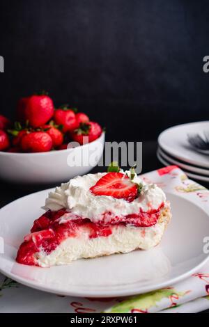 Fetta di torta alla fragola con panna montata: Fetta di torta di fragole ricoperta di panna montata e fragole fresche Foto Stock