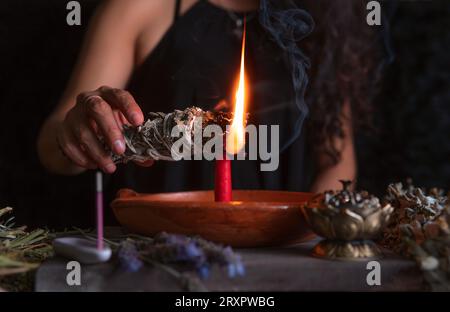Accendendo un incenso, strega alla vigilia di tutti i santi che esegue un rituale di pulizia, Halloween, credenze spirituali, magia bianca Foto Stock