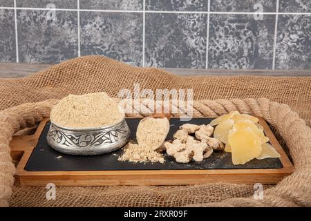 Rizoma di zenzero fresco e polvere di zenzero in un recipiente di legno. Cibo sano e speziato concetto. Zingiber officinale. Foto Stock