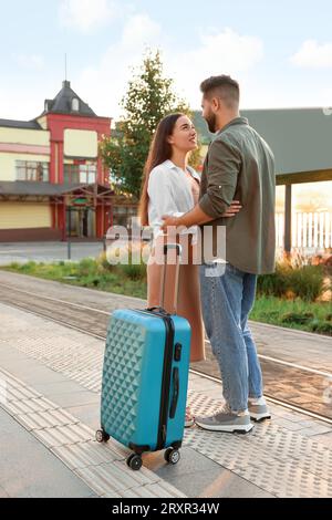 Relazione a distanza. Bella coppia giovane con valigia alla stazione ferroviaria all'aperto Foto Stock
