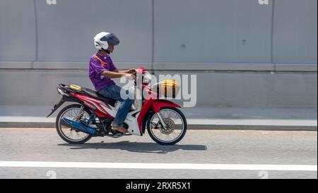 SAMUT PRAKAN, THAILANDIA, 19 settembre 2023, Un uomo guida una motocicletta in una strada cittadina Foto Stock