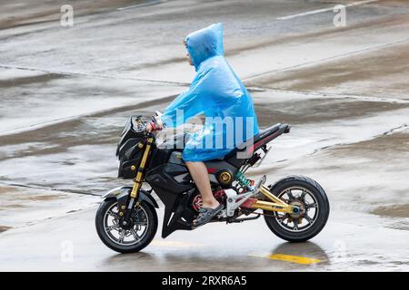 SAMUT PRAKAN, THAILANDIA, 20 settembre 2023, Un motociclista con un impermeabile guida una motocicletta sotto la pioggia Foto Stock