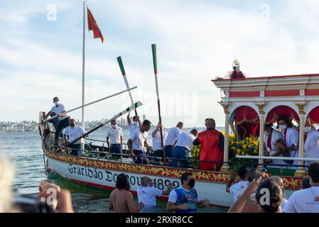 Salvador, Bahia, Brasile - 31 dicembre 2021: Si vede la barca Galiota lasciare la spiaggia con la statua di Gesù Cristo, il signore dei marinai, nel c Foto Stock