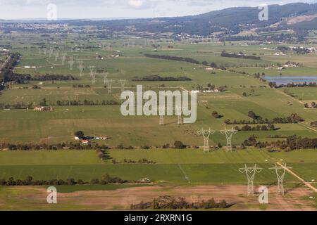 Vista dall'alto che mostra le linee elettriche che attraversano la tranquilla e verde campagna. Foto Stock